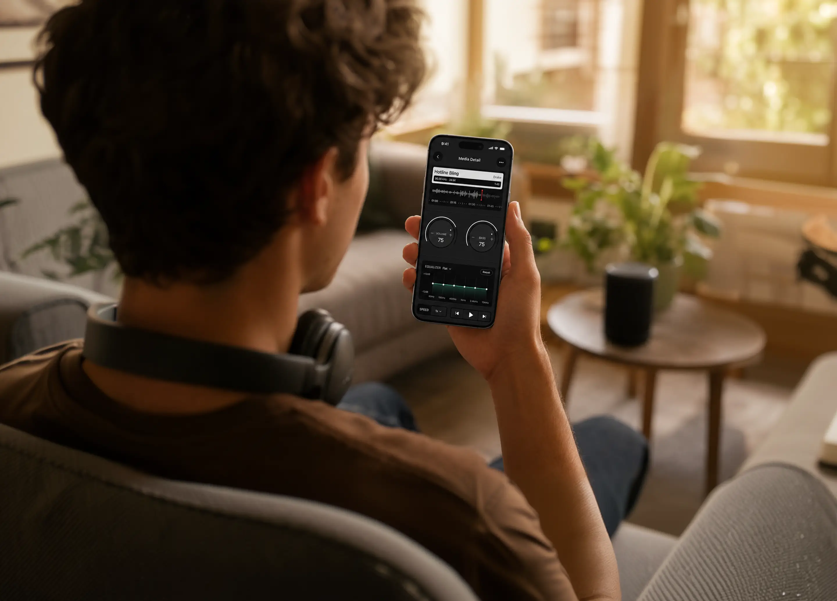 Someone listening to music on an iPhone running Volume Booster, with the volume, bass and equalizer controls on screen